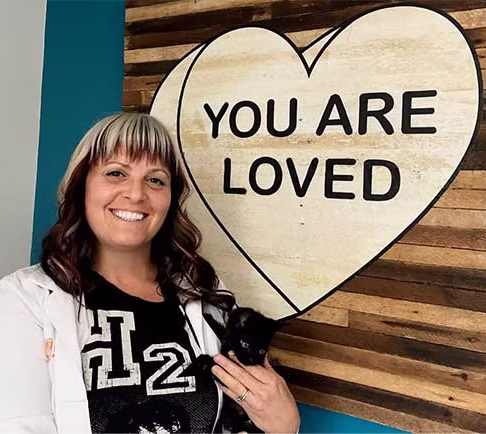 Dr. Cohn holding a kitten by a sign that says "you are loved"